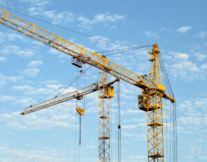 Two yellow crane systems against a blue sky in El Paso.